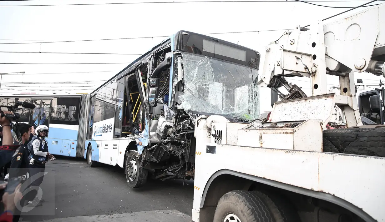 Badan bus Transjakarta dipindahkan dari lokasi kecelakaan di perlintasan Jalan Mangga Dua, Jakarta, Kamis (19/5). Sebelumnya, sebuah kecelakaan terjadi melibatkan bus transjakarta, mobil Avanza dan Kereta Senja Utama Solo. (Liputan6.com/Faizal Fanani)