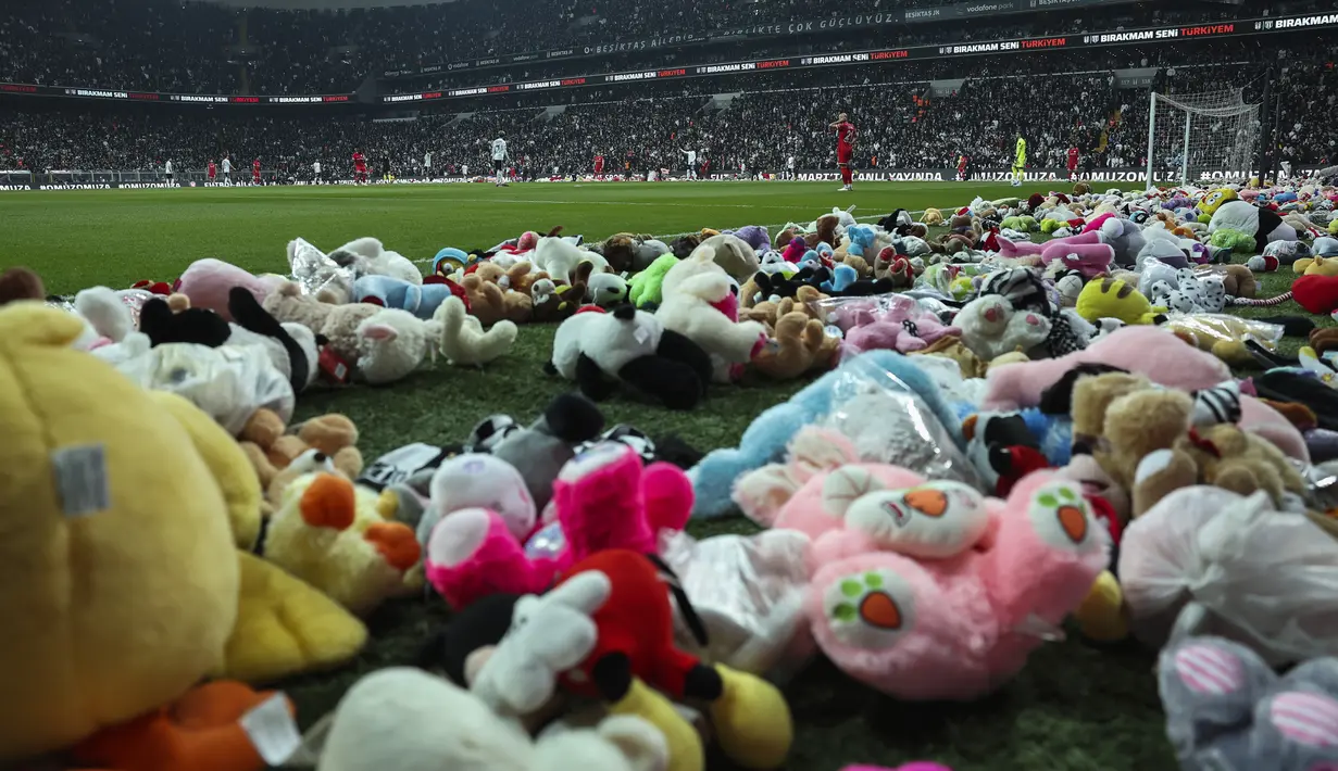 Para pemain melanjutkan permainan setelah para penggemar melemparkan mainan ke lapangan selama pertandingan Liga Turki (Super Lig) antara Besiktas dan Antalyaspor di stadion Vodafone di Istanbul, Minggu (26/2/2023). Lapangan dengan cepat ditutup, oleh pihak keamanan dan pemain memindahkan mainan untuk anak-anak korban gempa kuat Turki agar pertandingan dapat dilanjutkan. (AP Photo)