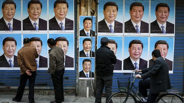 Warga menyaksikan poster bergambar Xi Jinping