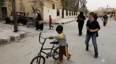 Sejumlah orang mulai kembali ke rumah mereka di kota modern Palmyra, berdekatan dengan kota kuno Suriah, Sabtu (9/4). Kota itu berhasil direbut kembali oleh militer Suriah dari tangan kelompok ekstrimis ISIS beberapa waktu lalu. (Louai BESHARA/AFP)