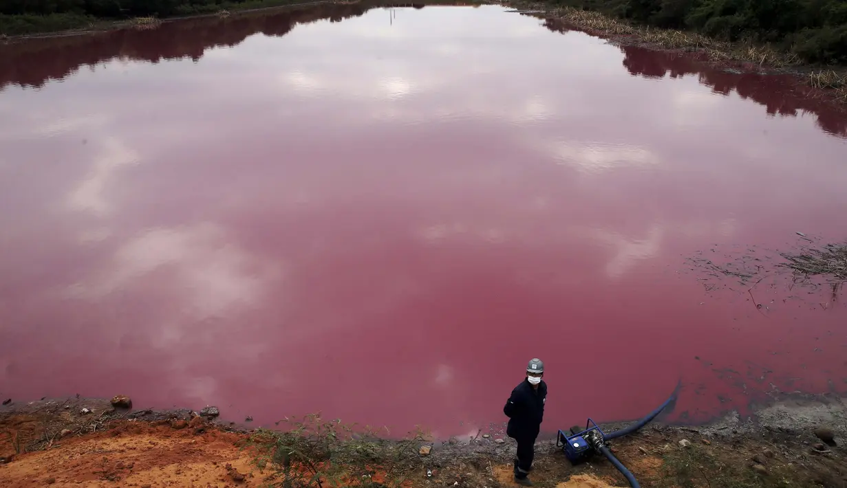 Seorang pekerja berdiri dekat pompa saat mengambil air untuk pengujian dari Cerro Lagoon yang berwarna merah muda dan berbau busuk di Limpio, Paraguay, 2 September 2020. Pencemaran air terjadi akibat limbah yang diduga berasal dari perusahaan penyamakan kulit Waltrading SA. (AP Photo/Jorge Saenz)