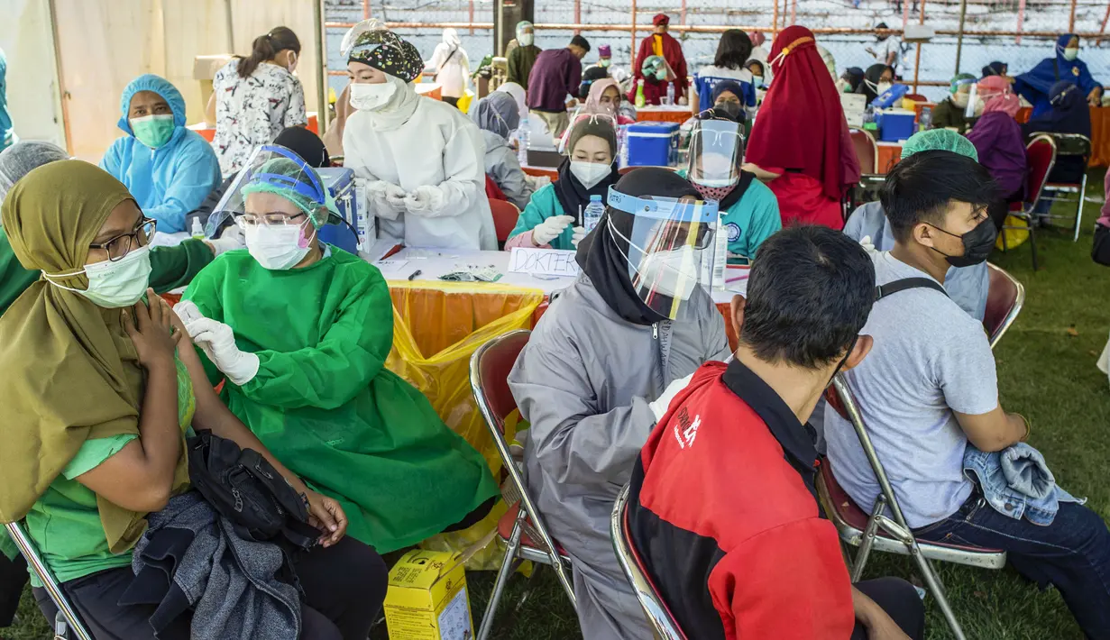 Warga menerima vaksin virus corona COVID-19 Sinovac di klinik vaksinasi massal darurat di lapangan sepak bola di Surabaya, Jawa Timur, Selasa (6/7/2021). Indonesia tengah memerangi gelombang infeksi baru yang belum pernah terjadi sebelumnya. (JUNI KRISWANTO/AFP)