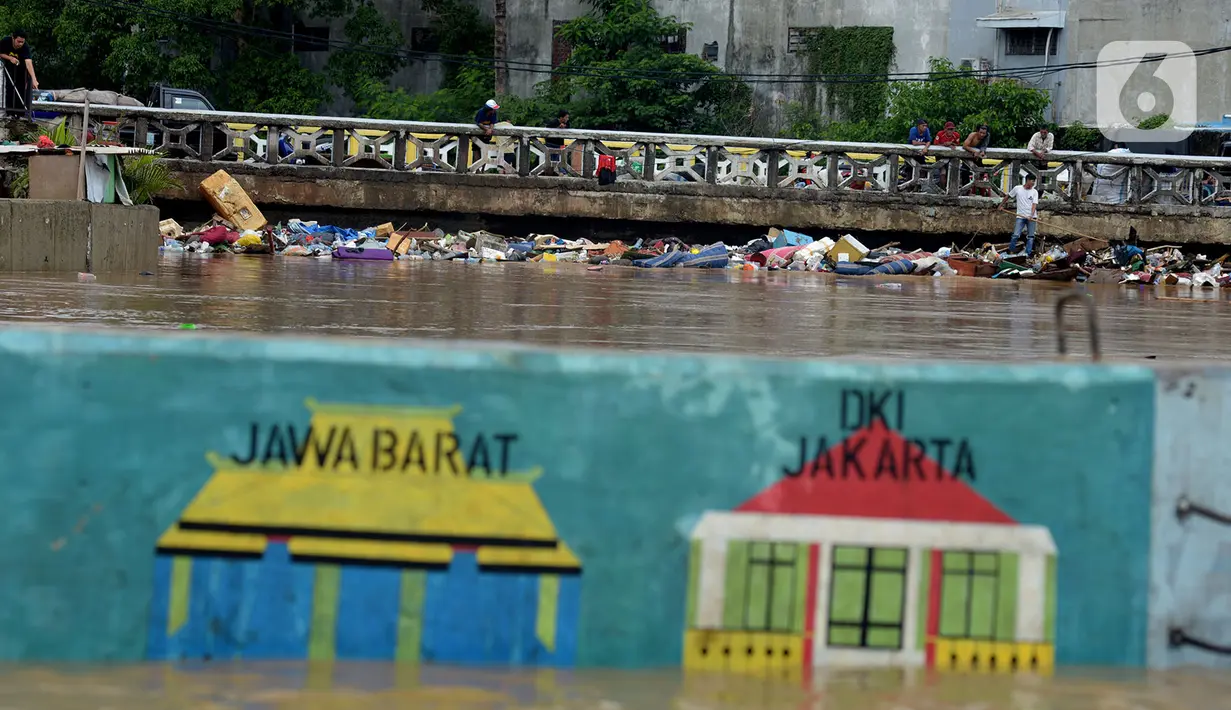 Tumpukan sampah tersangkut di sebuah jembatan di Jalan Jatinegara Barat, Jakarta, Kamis (2/1/2020). Hujan yang terjadi kemarin malam membuat Kali Ciliwung meluap ke jalan. (merdeka.com/Imam Buhori)