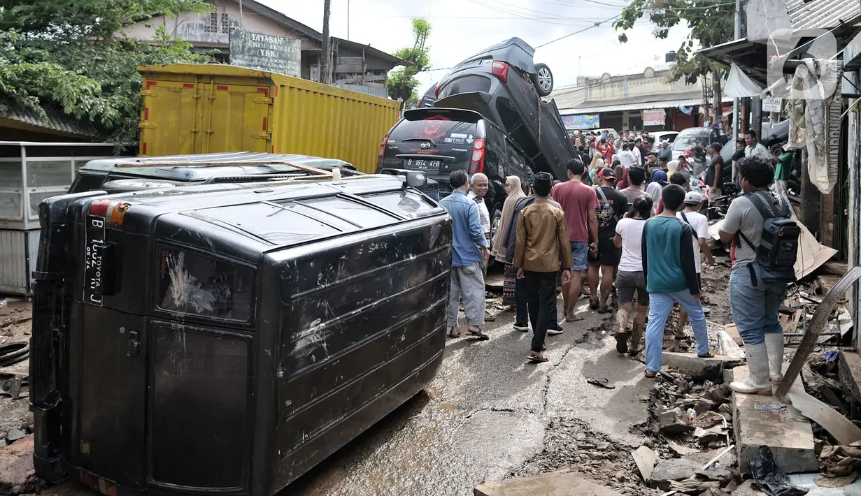 Warga mengerumuni sejumlah mobil yang terbalik akibat terjangan banjir di Perumahan Pondok Gede Permai, Jatiasih, Kota Bekasi, Jawa Barat, Kamis (2/1/2020). Derasnya terjangan banjir menyebabkan puluhan mobil terbalik dan belasan sepeda motor ringsek akibat terbawa arus. (merdeka.com/Iqbal Nugroho)