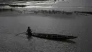 Seorang nelayan India mendayung perahu saat senja di air banjir surut di sawah di pinggiran Gauhati, India, Senin (14/9/2020). (AP Photo / Anupam Nath)