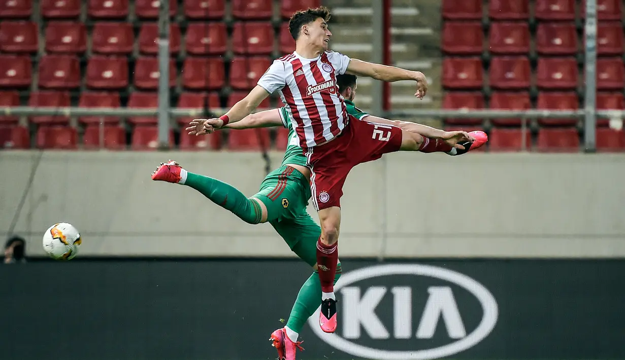 Bek Olympiakos, Kostas Tsimikas berebut bola udara dengan pemain Wolves, Matt Doherty pada leg perama babak 16 besar Liga Europa di Stadion Karaiskakis, Piraeus, Athena (12/3/2020). Tsimikas akan mengenakan seragam bernomor punggung 21 di Liverpool. (AFP/Angelos Tzortzinis)