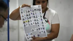 Seorang petugas pemilu menunjukkan surat suara saat penghitungan suara dimulai setelah pemungutan suara ditutup selama pemilihan umum di Guatemala City, Minggu, 25 Juni 2023. (AP Photo/Moises Castillo)