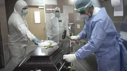 Anggota staf medis menyegel peti mati korban COVID-19 sebelum mengeluarkannya dari kamar mayat Rumah Sakit Darurat Universitas di Bucharest, Rumania, Senin (8/11/2021). Selama beberapa minggu terakhir Rumania melaporkan rekor jumlah infeksi dan kematian baru setiap hari. (AP Photo/Vadim Ghirda)