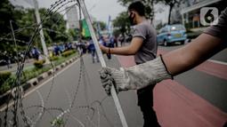 Personel kepolisian bersiap memasang kawat berduri untuk menjaga keamanan di sekitar Gedung DPR/MPR RI, Jakarta, Jumat (14/8/2020). Pengamanan ekstra itu untuk mengantisipasi rencana unjuk rasa menolak RUU Cipta Kerja yang bertepatan dengan Sidang Tahunan di Gedung DPR. (Liputan6.com/Faizal Fanani)