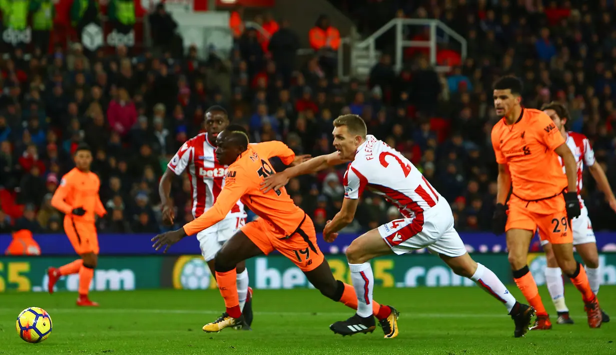 Gelandang Liverpool, Sadio Mane (kiri) berlari menggiring bola untuk mencetak gol ke gawang Stoke City pada pekan ke-14 Premier League di Bet365 Stadium, Kamis (30/11). Liverpool berhasil membantai Stoke City dengan skor 3-0. (Geoff CADDICK/AFP)
