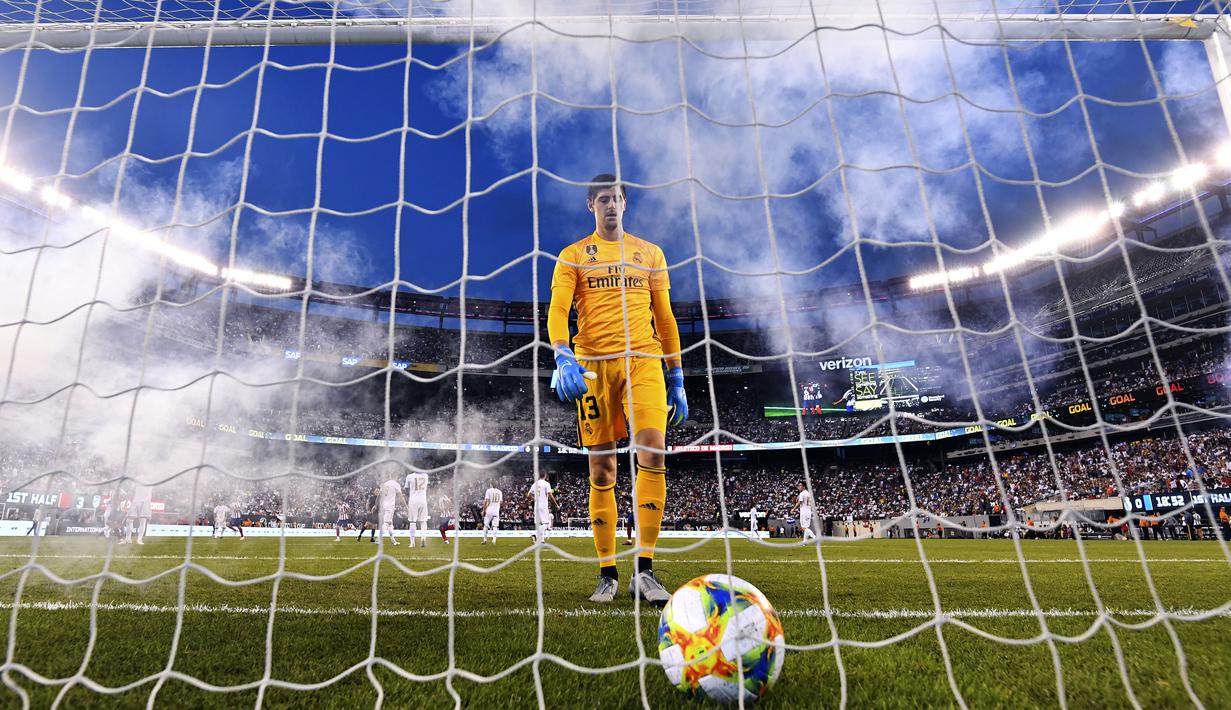 Kiper Real Madrid, Thibaut Courtois berjalan setelah bola masuk ke dalam gawang yang dijaganya selama laga International Champions Cup 2019 di Arena Stadium Metlife, New Jersey (27/7/2019). Atletico menang telak 7-2 atas Real Madrid. (AFP Photo/Johannes Eisele)