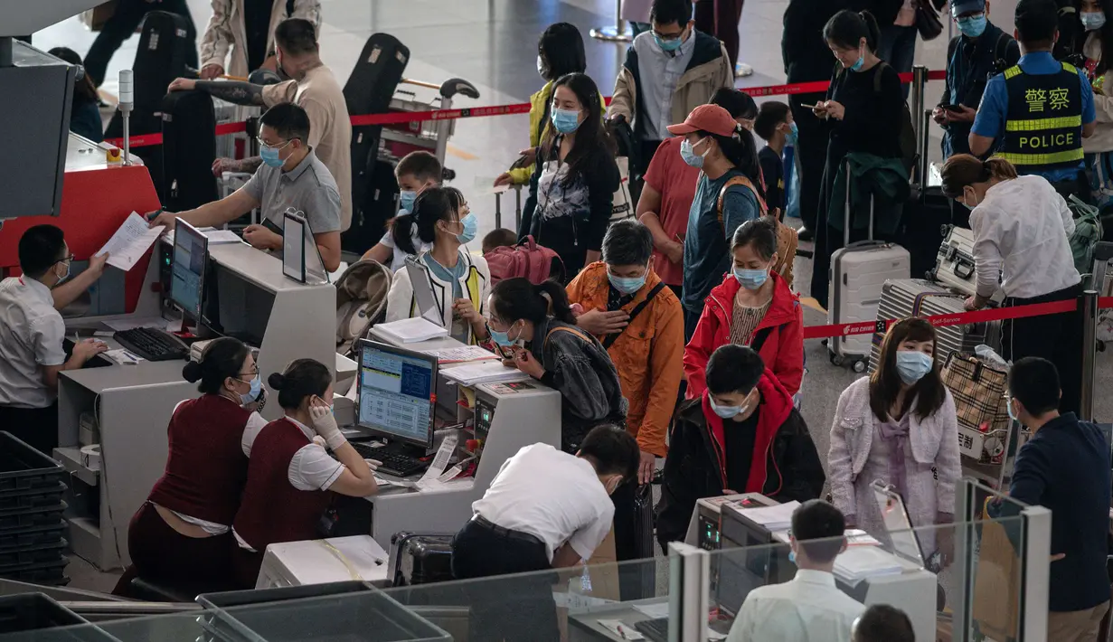 Orang-orang mengantre check-in untuk penerbangan domestik menjelang liburan "Golden Week" di Bandara Internasional Ibu Kota Beijing pada 30 September 2020. Gelombang liburan melanda China yang warganya merayakan libur panjang, yang dikenal dengan Golden Week. (NICOLAS ASFOURI / AFP)