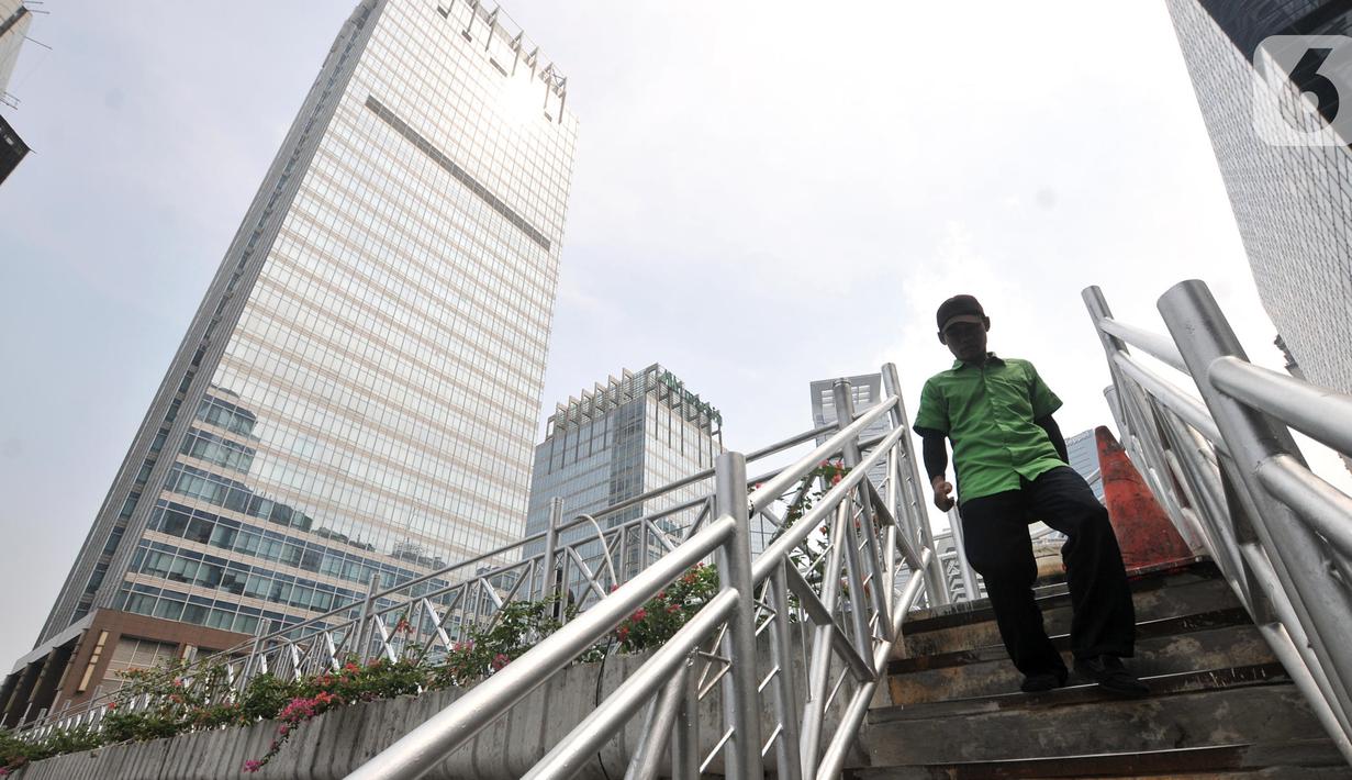 Pejalan kaki melintas di jembatan penyeberangan orang (JPO) yang tidak beratap di jalan Sudirman, Jakarta, Rabu (6/11/2019). Pemprov DKI melalui Dinas Bina Marga mencopot atap JPO Sudirman agar pejalan kaki dapat menikmati pemandangan gedung-gedung pencakar langit. (merdeka.com/Iqbal Nugroho)