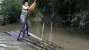 Seorang anak laki-laki berjalan dengan rakit bambu melalui air banjir di daerah Kanaighat di Sylhet, Bangladesh (23/5/2022). Banjir bandang pra-musim telah membanjiri bagian dari India dan Bangladesh, menewaskan sedikitnya 24 orang dalam beberapa pekan terakhir dan mengirim 90.000 orang ke tempat penampungan. (AP Photo)