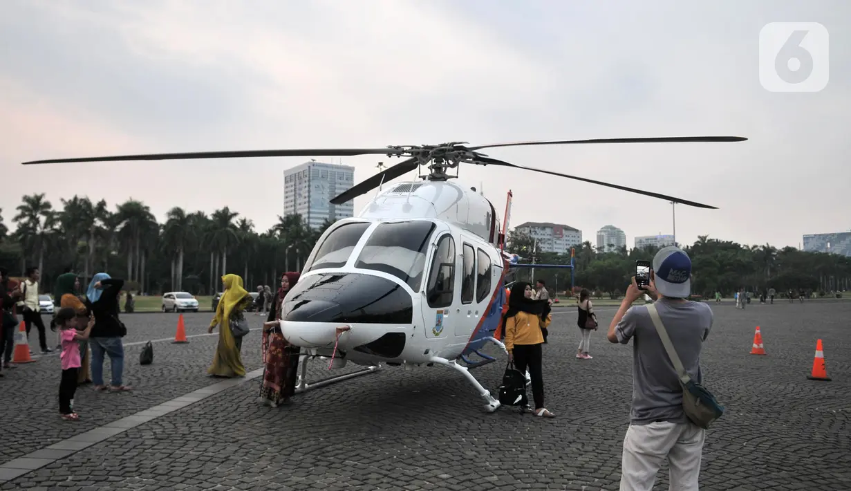 Warga berfoto dengan helikopter Polri yang terparkir di kawasan Monas, Jakarta, Rabu (16/10/2019). Kehadiran empat helikopter TNI/Polri yang akan digunakan dalam apel pengamanan pelantikan presiden dan wakil presiden tersebut menarik perhatian pengunjung Monas. (merdeka.com/Iqbal Nugroho)