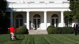 Presiden AS, Donald Trump melihat anak laki-laki, Frank Giaccio mendorong mesin pemotong rumput di Rose Garden, Gedung Putih, Jumat (15/9). Dalam kesehariannya, bocah 11 tahun itu menjalankan bisnis perawatan rumah bersama ayahnya. (AP/Jacquelyn Martin)