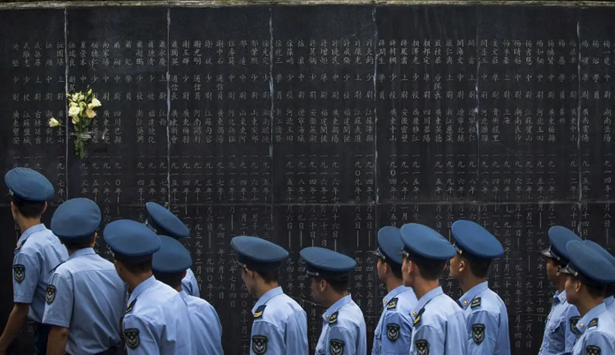 Beberapa anggota militer melintasi monumen yang bertuliskan nama-nama orang yang gugur dalam pertempuran melawan Jepang selama Perang Dunia II di Aviation Martir Memorial di Nanjing, (3/9/2014). (AFP PHOTO/STR)