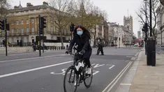 Seorang wanita mengenakan masker saat dia bersepeda di Westminster, di London, Kamis (16/12/2021). Inggris mencatat jumlah tertinggi infeksi COVID-19 baru yang dikonfirmasi pada hari Rabu (15/12) sejak pandemi dimulai. (AP Photo/Alberto Pezzali)