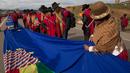Seorang wanita menyatukan bagian-bagian bendera biru raksasa di jalan raya antara Oruro dan La Paz Bolivia (10/3). Gerakan ini untuk mendukung usaha negara Bolivia untuk mendapatkan akses berdaulat ke laut. (AP Photo / Juan Karita)
