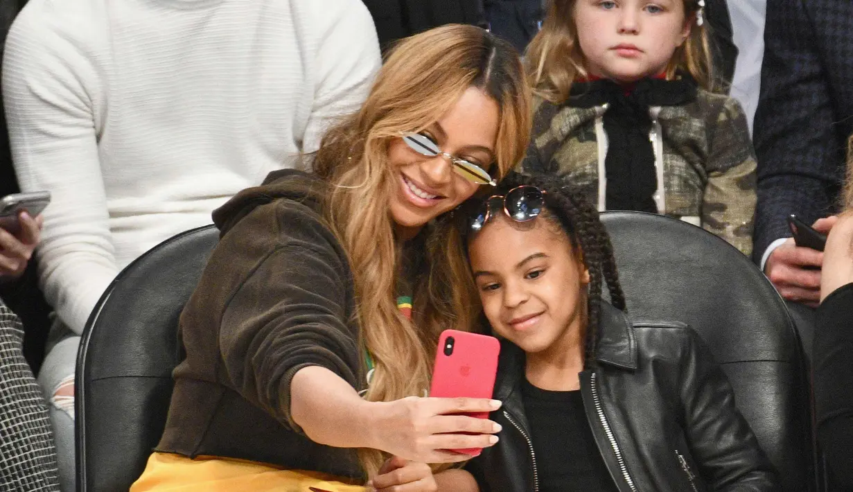 Penyanyi Beyonce dan putrinya Blue Ivy Carter berselfie saat menonton pertandingan NBA All-Star Game 2018 di Staples Center di Los Angeles, California, AS (18/2). (Allen Berezovsky/Getty Images/AFP)