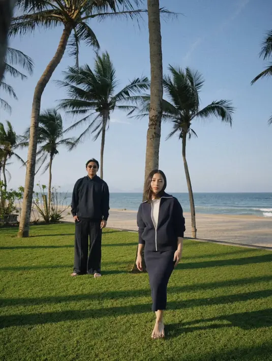 Momen paling intim terlihat saat keduanya berjalan di hamparan rumput hijau dengan latar pantai dan langit biru. Nikita mengenakan set navy berupa zip-up top dan rok midi yang sleek, menciptakan kesan sporty-elegant. Rambut tergerai natural membuat tampilannya terasa effortless. [@nikitawillyofficial94].