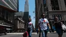 Orang-orang berjalan melewati Gedung Chrysler pada hari yang hangat di New York City (7/6/2021). Cuaca yang hangat di New York dimanfaatkan warga untuk membaca buku hingga berjalan-jalan. (AFP/Angela Weiss)
