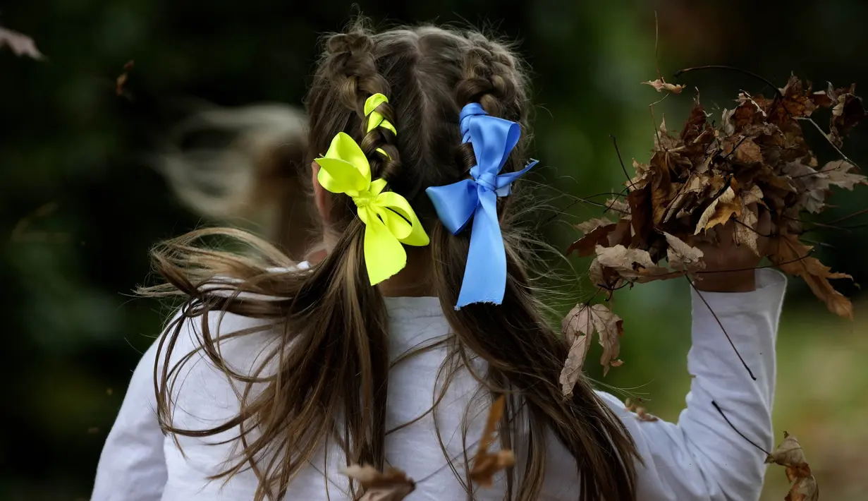Anak-anak dengan pita warna nasional Ukraina di rambut mereka bermain di perayaan hari Kemerdekaan Ukraina di sebuah perayaan di Chichester, Inggris selatan, Sabtu, 27 Agustus 2022. Chichester dinobatkan sebagai daerah paling dermawan di negara itu untuk menampung pengungsi Ukraina. (AP Photo/Frank Augstein)