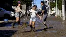 Anak-anak membersihkan lumpur dari jalan setelah banjir surut di Kawasaki, Minggu (13/10/2019). Topan dahsyat Hagibis yang menerjang sejumlah wilayah di Jepang menyebabkan banjir di beberapa lokasi. (Photo by WILLIAM WEST / AFP)
