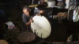Pembuat rebana tradisional, Fajar Siddiq menyelesaikan pembuatan rebana di rumahnya di Lambaro, Provinsi Aceh, Senin (22/2/2021). Usaha produksi berbagai jenis alat musik tradisional Aceh berupa rapai, serune kale dan seruling mulai langka. (CHAIDEER MAHYUDDIN / AFP)