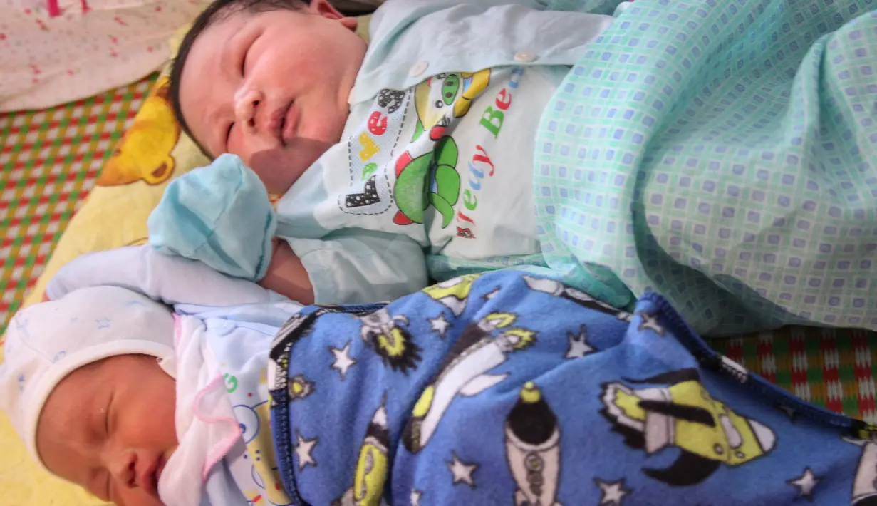 Seorang bayi laki-laki, Tran Tien Quoc (atas) sedang tidur di samping bayi laki-laki tidak dikenal di pusat kesehatan Vinh Tuong, provinsi Vinh Phuc, Minggu (15/10). Ibu asal Vietnam melahirkan bayi laki-laki itu dengan berat 7,1 kilogram. (LE PHUONG/AFP)