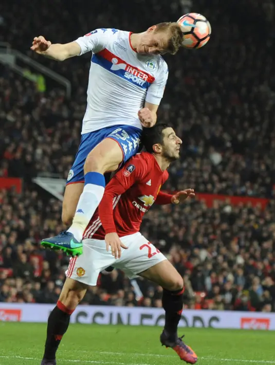 Gelandang MU, Henrikh Mkhitaryan berebut bola udara dengan bek Wigan Athletic, Dan Burn pada pertandingan Piala FA di Stadion Old Trafford, Inggris (29/1). Manchester United  melaju ke babak 16 besar Piala FA. (AP Photo/Rui Vieira)