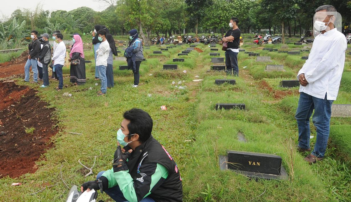 Keluarga menyaksikan pemakaman korban COVID-19 di TPU Pondok Ranggon, Cipayung, Jakarta Timur, Rabu (1/4/2020). Hari ini di TPU Pondok Ranggon hingga menjelang sore hari tercatat sembilan belas jenazah dimakamkan baik yang berstatus ODP, PDP  maupun postif  COVID-19. (merdeka.com/Arie Basuki)