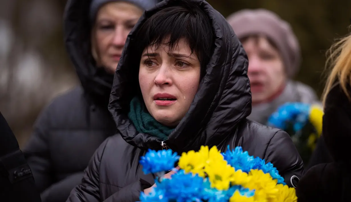 Seorang wanita menangis saat upacara peringatan satu tahun dimulainya perang Rusia-Ukraina, di sebuah pemakaman di Bucha, Ukraina, Jumat, 24 Februari 2023. (AP Photo/Emilio Morenatti)