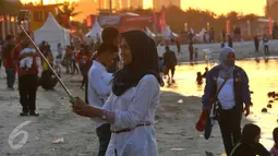 Pengunjung berselfie sambil menimmati pemandangan di pantai Ancol, Jakarta, (31/12). Pemprov DKI Jakarta menyarankan untuk warga Jakarta yang ingin merayakan malam pergantian tahun di pusatkan di Pantai Ancol. (Liputan6.com/Gempur M Surya)