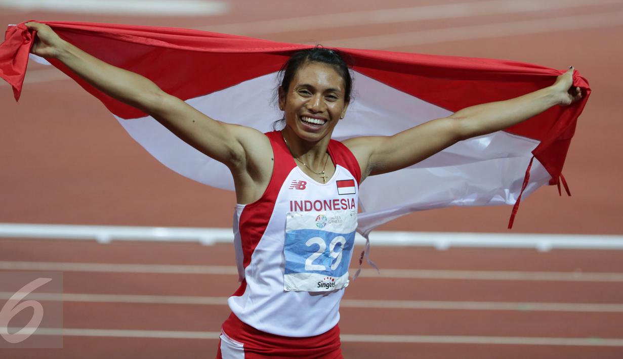 Atlet putri Indonesia, Maria Londa membentangkan Merah Putih usai memastikan meraih emas cabang atletik nomor lompat jangkit di National Stadium, Singapura, Kamis (11/6/2015). Maria mencatat lompatan sejauh 13,75 meter. (Liputan6.com/Helmi Fithriansyah)