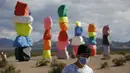 Seorang pria berjalan di instalasi seni Seven Magic Mountains karya seniman Ugo Rondinone di Las Vegas, Amerika Serikat, Selasa (7/4/2020). Seven Magic Mountains mulai dibuka untuk umum pada bulan Mei 2016 lalu. (AP Photo/John Locher)