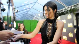 Model cantik Kendall Jenner menandatangani auographs sebelum memasuki karpet merah MTV Movie Awards 2016 di Burbank, California, Sabtu (9/4). Kendall mencuri perhatian dalam balutan gaun hitam menerawang yang seksi (Emma McIntyre/Getty Images for MTV/AFP)
