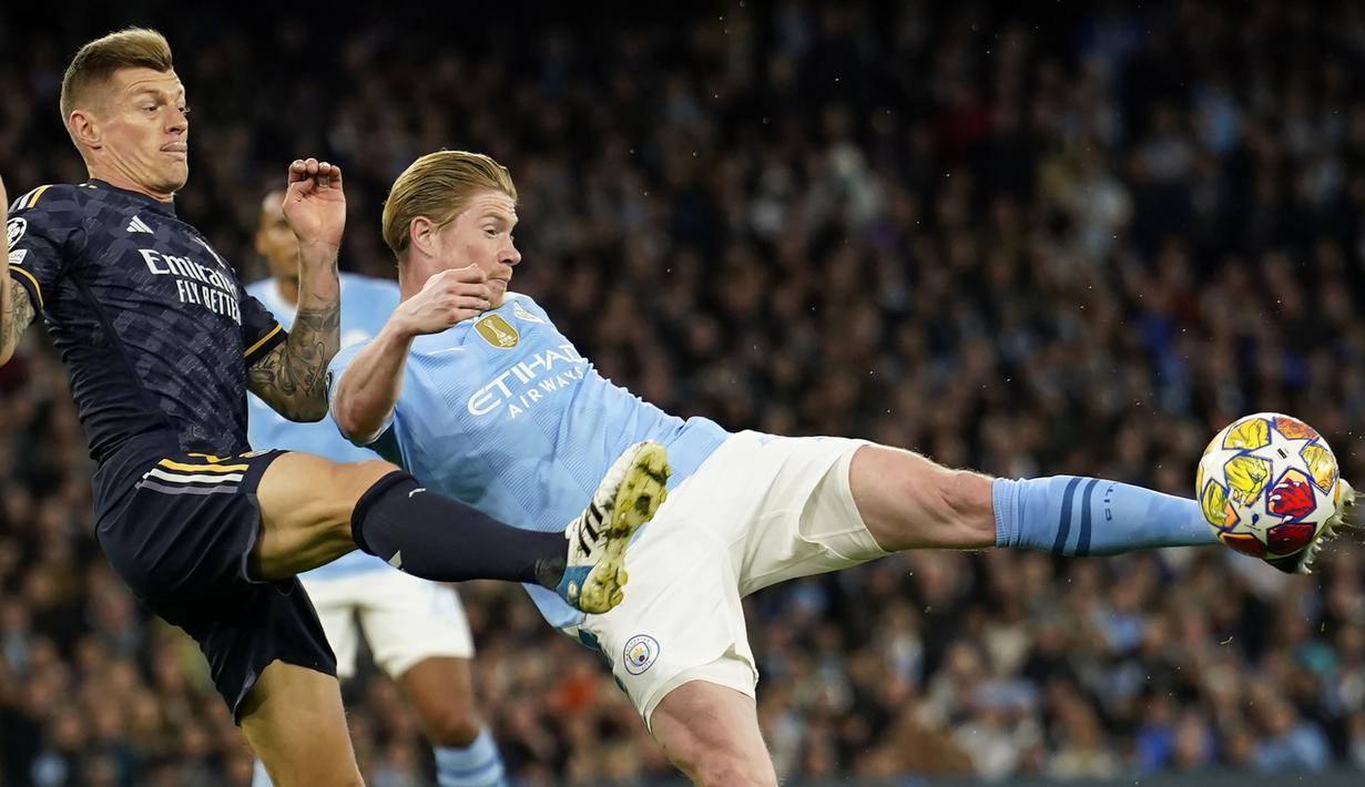 Gelandang Manchester City, Kevin De Bruyne melepaskan tendangan di bawah tekanan gelandang Real Madrid, Toni Kroos pada laga leg kedua perempatfinal Liga Champions 2023/2024 di Etihad Stadium, Manchester, Rabu (18/4/2024). (AP Photo/Dave Thompson)
