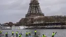 Peserta menyeberangi sungai Seine dekat menara Eiffel selama Nautic Paddle Race di Paris, Minggu (9/12). Sekitar 800 orang mengikuti lomba dayung sambil berdiri terbesar di dunia sejauh 11 km dengan pemandangan kota Paris. (Lucas BARIOULET/AFP)