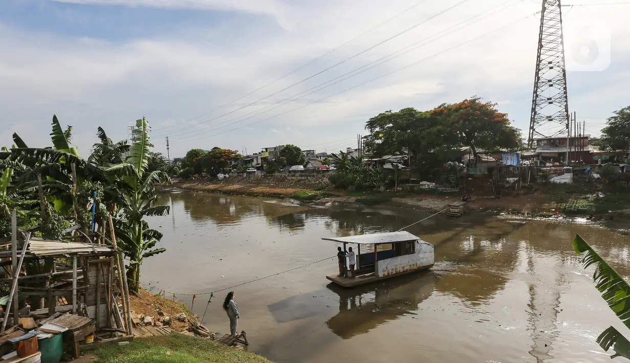 Perahu eretan membawa warga menyeberangi Banjir Kanal Barat, Jatipulo, Jakarta, Senin (31/01/2022). Jasa transportasi tradisional, perahu eretan yang beroperasi sejak tahun 1990 hanya dikenakan tarif Rp 2000 sekali menyeberang dari pagi hingga sore hari. (Liputan6.com/Fery Pradolo)