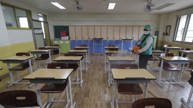 Pekerja mengenakan masker saat mendisinfeksi kelas di Sekolah Menengah Putri Yeouido, Seoul, Korea Selatan, Selasa (19/5/2020). Sekolah-sekolah di Korea Selatan secara bertahap akan mulai dibuka pada 20 Mei 2020. (AP Photo/Ahn Young-joon)