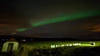 Aurora borealis atau Cahaya Utara terlihat di atas lahan pertanian dekat air terjun Godafoss di Thingeyjarsveit, Islandia, 14 Oktober 2018. Lukisan abstrak alam semesta dari tabrakan spektrum warna Aurora Borealis begitu spektakuler. (Mariana SUAREZ/AFP)