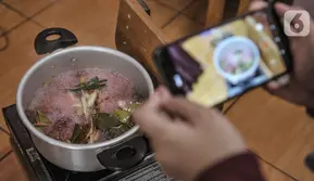 Pendidik merekam proses pembuatan bir pletok saat kelas sentra memasak via virtual di Pendidikan Anak Usia Dini (PAUD) Cempaka, Tebet Barat, Jakarta, Senin (23/11/2020). Selama pandemi Covid-19, pendidik di PAUD Cempaka rutin menggelar kegiatan belajar secara virtual. (merdeka.com/Iqbal S Nugroho)