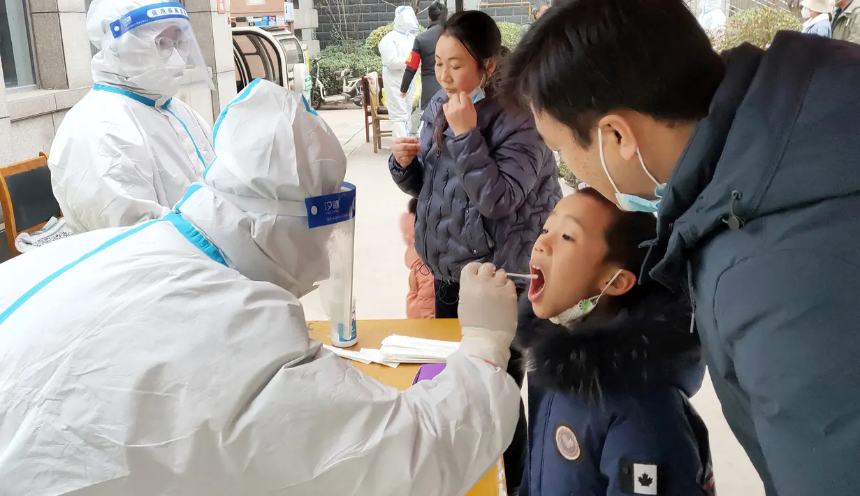 Seorang anak menjalani tes asam nukleat untuk virus corona Covid-19 di Anyang di provinsi Henan, China tengah pada 12 Januari 2022. China sedang berjuang melawan covid di beberapa kota, beberapa minggu sebelum Beijing menjadi tuan rumah Olimpiade Musim Dingin 2022. (STR/AFP)