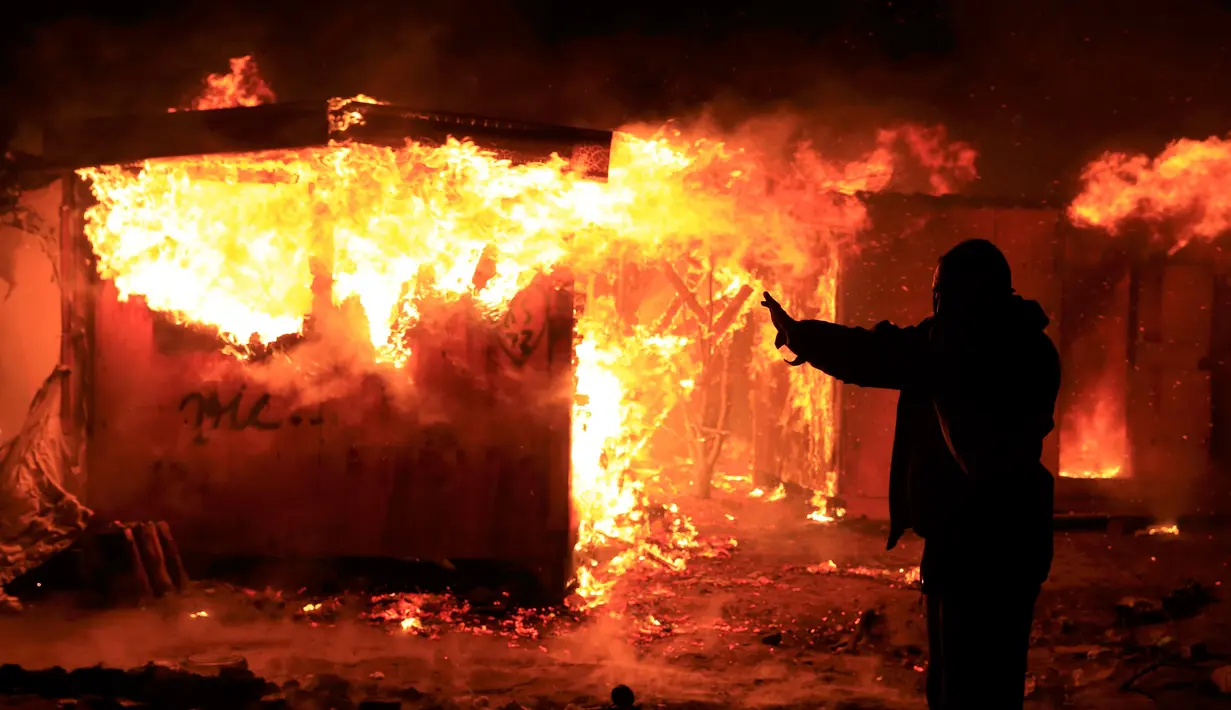 Imigran berdiri di depan tempat tinggalnya yang dibakar pihak berwenang di lahan kumuh yang dijuluki "Jungle" di Calais, Prancis (1/3). Pembakaran ini memunculkan protes bagi ribuan imigran yang tinggal di lokasi tersebut. (REUTERS/Pascal Rossignol)