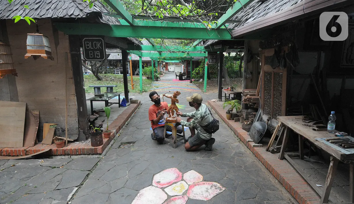 Pengunjung memperhatikan seniman menyelesaikan karya patung di Pasar Seni Ancol, Jakarta, Rabu (24/11/2021). Paska pandemi yang berlangsung dua tahun, sejumlah seniman di Pasar Seni Ancol mulai beraktifitas menjadikan karya-karyanya sebagai sumber daya hidup mereka. (merdeka.com/Arie Basuki)
