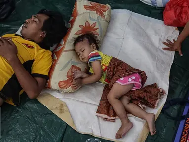 Seorang ayah dan putrinya tengah tertidur di kelas SD Kristen Fajar Sion, Jakarta Barat, Minggu (8/1). Sebanyak 110 rumah di pemukiman padat penduduk di Jalan Pangeran Jayakarta habis dilalap si jago merah. (Liputan6.com/Fery Pradolo)