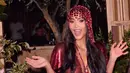Dengan ekspresi ceria dan kedua tangan terangkat, Kim tampil semringah di meja pesta berhias bunga mawar. Kilau gaun mesh merah semakin terlihat di bawah cahaya lilin, berpadu kalung kristal dan penutup kepala senada. [@kimkardashian]