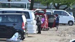 Dua orang wanita berdiri di dekat mobil mereka di Mashiki, prefektur Kumamoto, Jepang, 17 April 2016. Gempa yang terjadi pada Kamis (14/4) malam membuat banyak warga lebih memilih untuk mengungsi dan tidur di mobil mereka sendiri. (Kazuhiro NOGI/AFP)