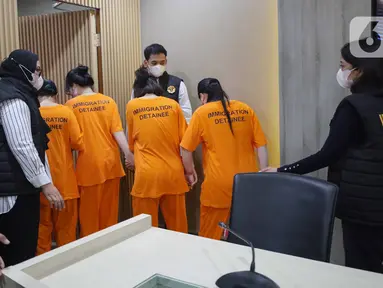 Petugas menggiring Warga Negara Asing (WNA) asal Vietnam yang tertangkap usai rilis penangkapan pelanggar izin tinggal di kantor Direktorat Jenderal (Ditjen) Imigrasi, Jakarta, Jumat (10/1/2025). (Liputan6.com/Angga Yuniar)